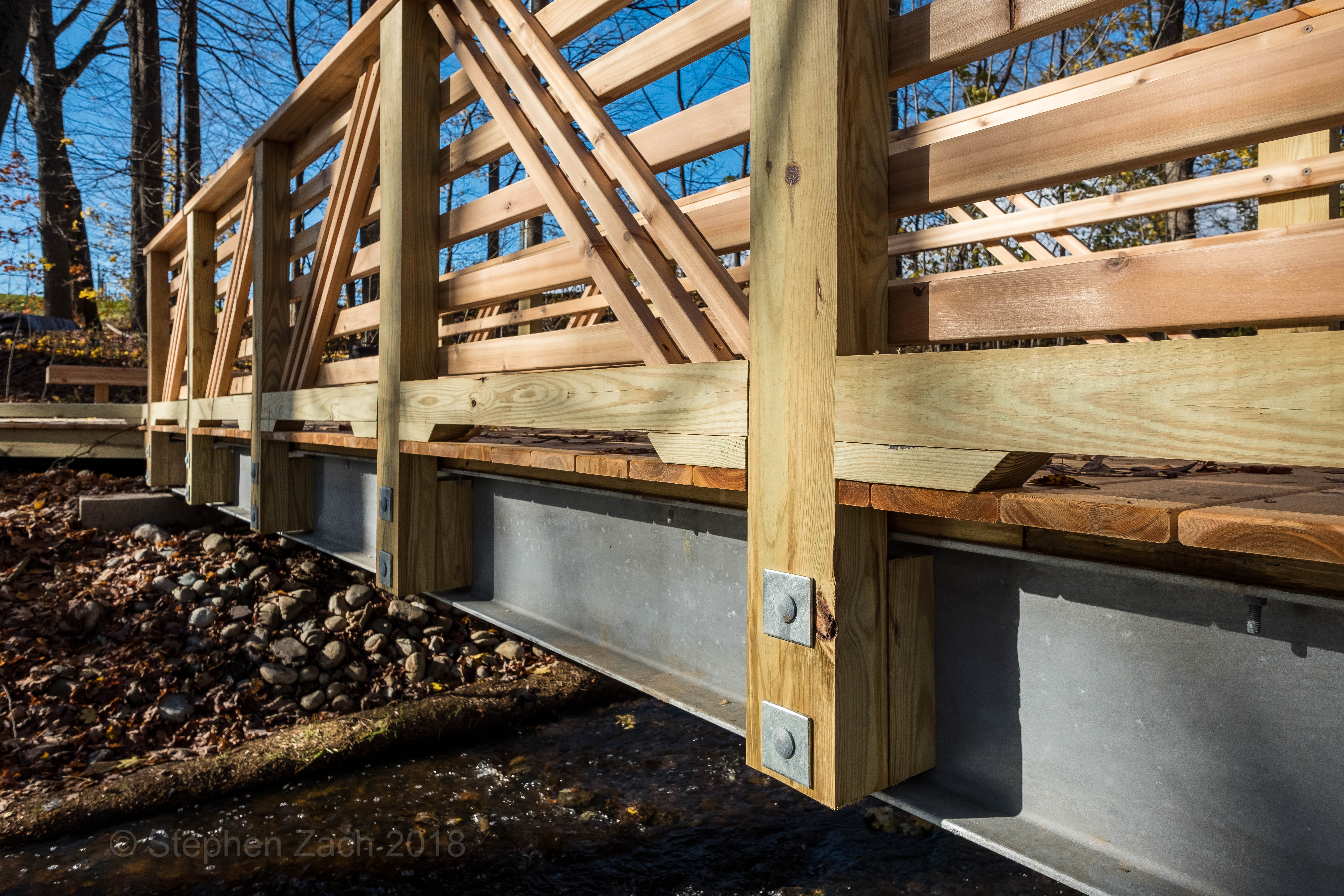 Wooden footbridge over creek with metal supports