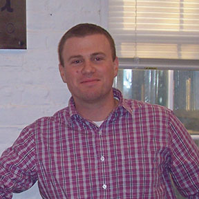 Smiling man wearing plaid shirt indoors
